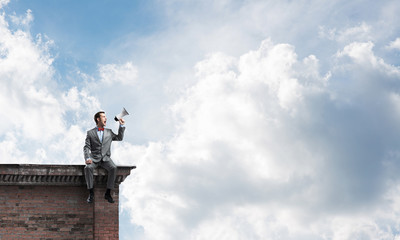 Businessman or manager on building roof announcing something in loudspeaker