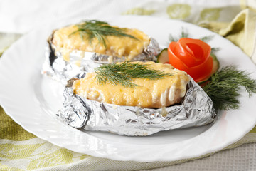 fish in foil with cheese and greens on a plate