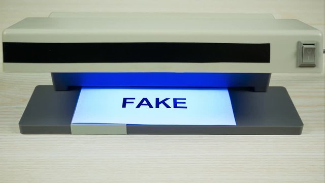 Concept of fake emotions, insincerity. The word "emotions" on a white paper under the detector becomes a word "fake". Stop motion