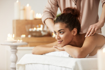Obraz na płótnie Canvas Beautiful african girl smiling enjoying massage in spa resort.