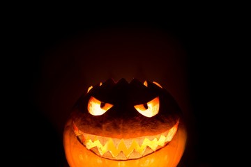 Fototapeta premium Bottom halloween pumpkin smile with hot burning fire eyes mouth. Big spooky helloween symbol has a glowing mad face and smiling with sharp teeth and bad look. Black orange nightmare of October 31st