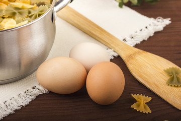 Chicken eggs on the table. Macaroni farfalle colored