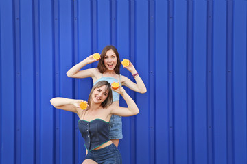 Two young woman with orange fruit on blue background