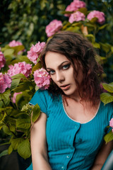 Young woman with curly hair enjoying the scent of hydrangea. Perfectly retouched. Concept of perfume advertising.