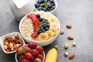 Oat flakes in bowl with berries and milk on wooden table