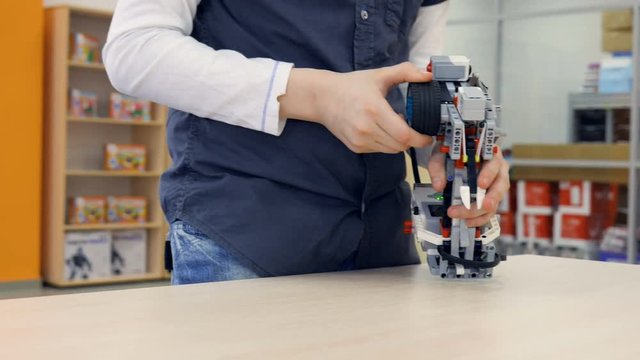 School boy engineer controls wireless robot. Close-up.