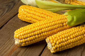 Ripe yellow sweet corn cob on a wooden table close-up