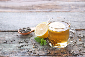 Cup of tea with lemon and mint on wooden table