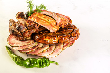 Delicious pork ribs, homemade sausage, meatloaf and bitter green pepper on a light marble background. Not isolated.