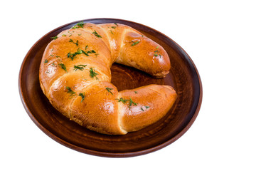 Freshly baked large  croissant, sprinkled with dill. On a clay dish. Isolated on white background.