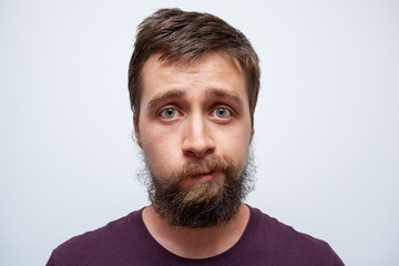 Young bearded man uncertain what to do with his messy beard and moustache - obrazy, fototapety, plakaty