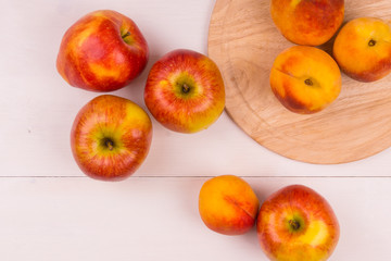 Ripe apples and peaches on a wooden table. Ripe fruit on a light background - top view.