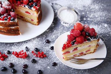 Homemade biscuit cake with berries and powdered sugar on grey wooden table