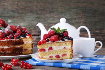 Homemade biscuit cake with berries and cup of tea on grey wooden table