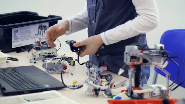School boy assembling model kit of a futuristic robot. 4K.