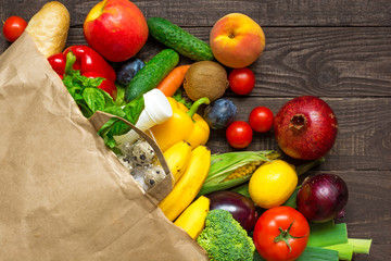 Full paper bag of different health food on rustic wooden background