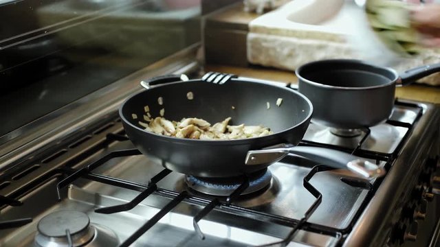 Girl cooks vegetables in wok at home, adds ingredients, vinegar, soy sause, stir and mix and salts and peppers. Healthy and tasty vegan food cooking concept.