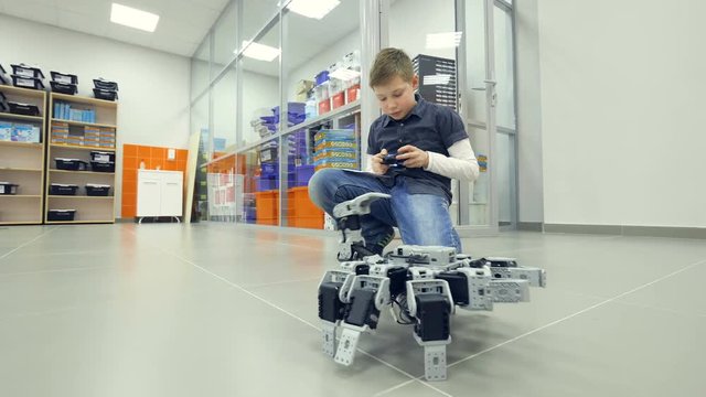 Smart school boy controlls wireless robot. 4K.