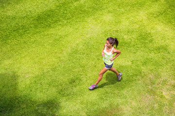 Fototapeta na wymiar Active sport woman runner running on grass outdoors training for marathon. Asian chinese sporty girl on morning run.