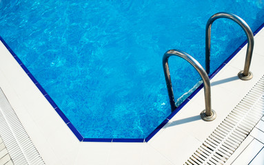 Grab bars ladder in the blue swimming pool