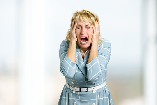 Mature Woman Screaming In Despair. Close Up Shot Of Stressed And Shocked White-skin Woman Screaming With Desperate And Horrified Expression, Hands On Head.