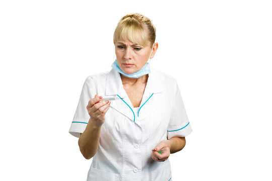 Female Doctor Looking On Thermometer. Frowning Middle Aged Nurse Checking Temperature, White Background.