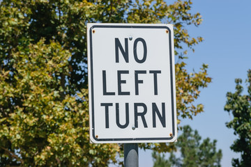No left turn sign with trees and blue sky background