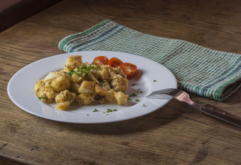 close up bread dumpling with fried eggs cheese chive tomatoes with fork and table napkin on old wooden table