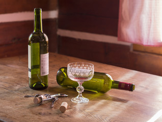 morning after booze-up two empty bottles of red wine and glass two cork and corkscrew on wooden table