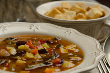 Vegetables soup served with croutons, rustic background 