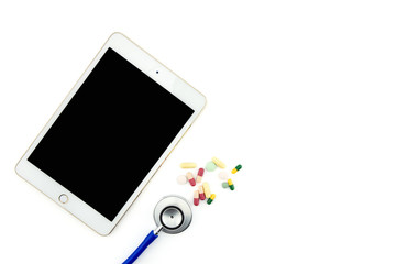 Top view of doctor desk with digital tablet with empty screen. Top view of medical equipment, medicine, pills and stethoscope. Helthcare and healthy concept.