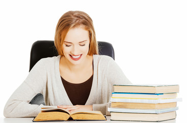 Beautiful student woman sitting by the desk with books and learn