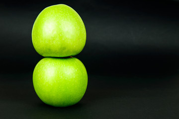 Two green apples on dark background