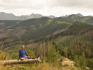 Girl practicing yoga in the mountains. Gymnastics on a log