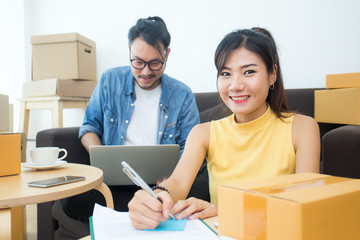 Young Asian People Working at home, Young Owner People Strat up for Business Online, SME, Delivery Project, People with Online Business or SME Concept. Woman Note Order from Customer.