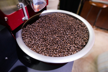 Arabica coffee beans in coffee machine roasting process.Coffee roasters machine. roasted coffee beans in spinning cooler professional machine.selective focus