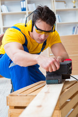 Repairman carpenter polishing a wooden board with an electric po