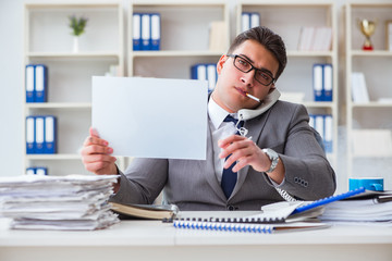 Businessman smoking at work in office holding a blank message bo