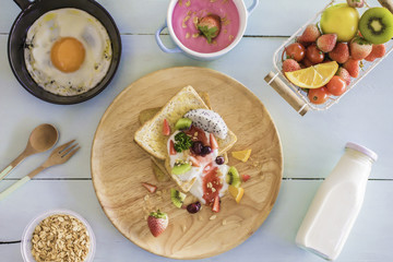 Toast and fruit total milk yogurt with fried egg in a frying pan on wood Top view.