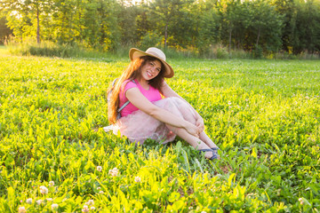 Beautiful young laughing naughty woman sitting on the grass and smiling