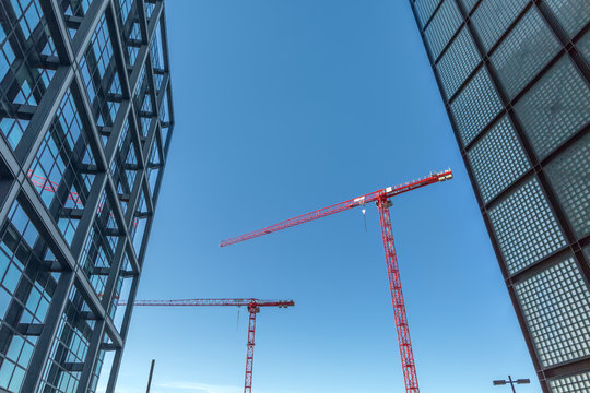 Red tower cranes between buildings