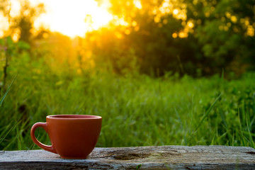 Morning cup of coffee on wooden table at sunrise