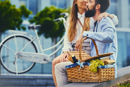 Image of a couple with picnic basket over modern building background.