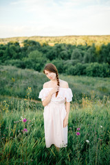 Beautiful girl walking on the grass field on the evening sun