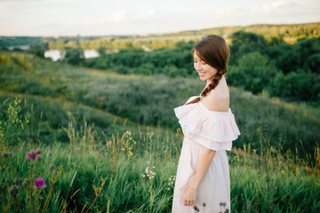 Fototapeta na wymiar Beautiful girl walking on the grass field on the evening sun
