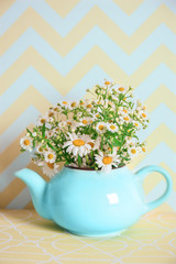 Beautiful bouquet of chamomile flowers in teapot on table