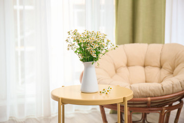 Beautiful bouquet of chamomile flowers in jug on table