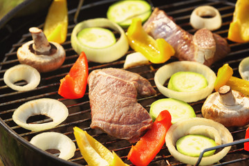 Raw meat and vegetables on barbecue grill, close up