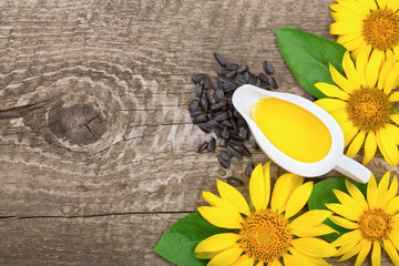 Sunflower oil, seeds and flower on wooden background with copy space for your text. Top view