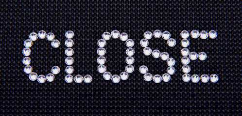 Word CLOSE is made rhinestones on a black canvas background.
